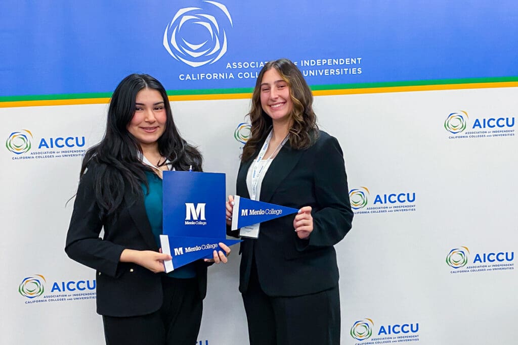 Two Menlo College students standing in front of a AICCU banner at the Capitol