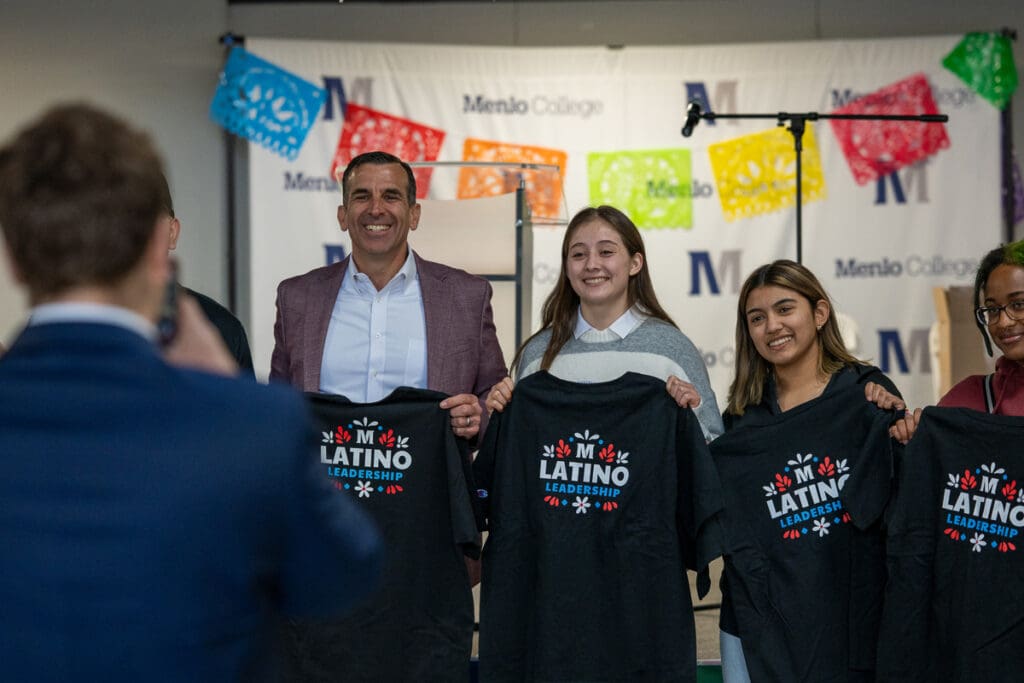 Congressman holds up Latino Leadership t-shirts with Menlo College students.