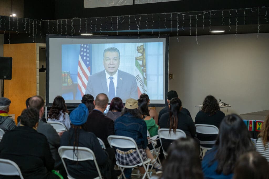 Guest speaker via video broadcast is addressing a crowd.