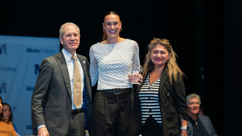 Menlo College President Steven Weiner (left) and Dr. Sonia Tahereh Saheb (right) present an academic award to student Frida Schmidt during Menlo College's 2026 Honors Convocation. Schmidt stands between them holding the award as the three smile on stage during the annual ceremony recognizing outstanding academic achievement, leadership, and service.