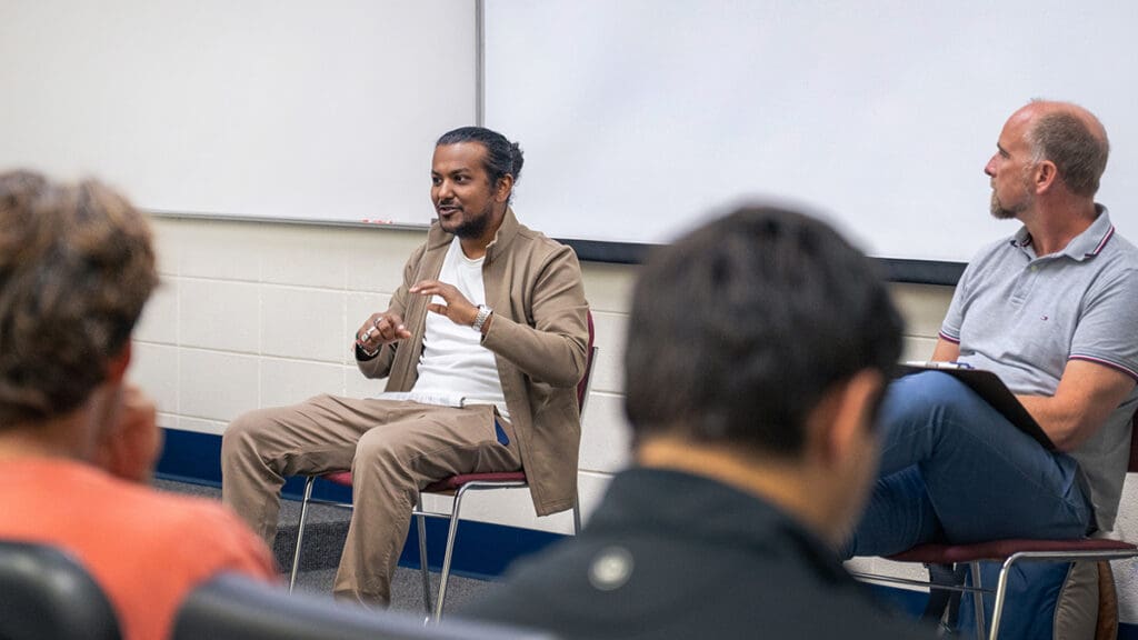 Menlo College alumnus Sam Thapaliya (left) gestures while speaking to students about Entrepreneurship Through Acquisition as Dr. Fabian Eggers sits beside him, listening during a classroom discussion.