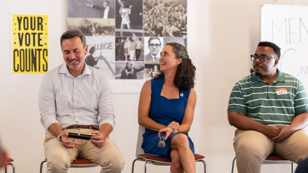 From left, San Mateo County Supervisor Ray Mueller smiles while looking down, Dr. Melissa R. Michelson laughs while holding a microphone, and election outreach coordinator Chephren Goree looks toward fellow panelists during the Civic Engagement Forum at Menlo College.