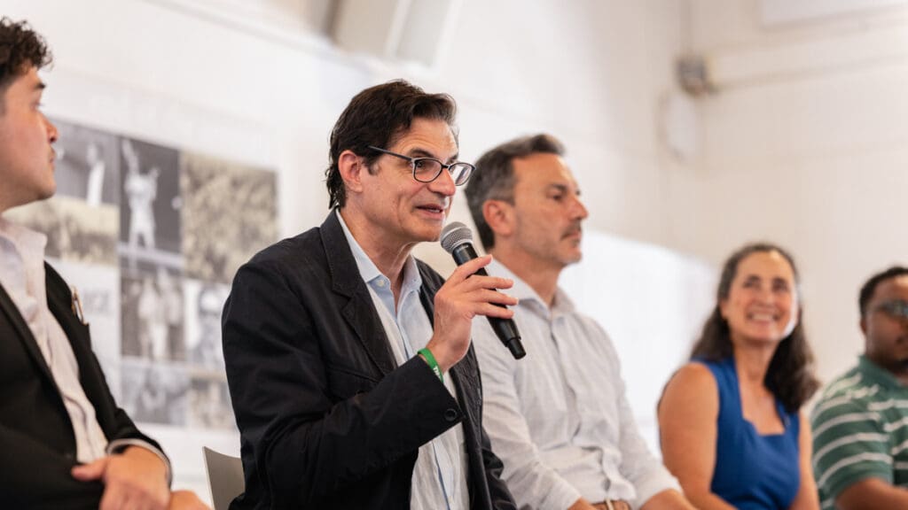 California State Senator Josh Becker speaks into a microphone during the Civic Engagement Forum at Menlo College on October 7, 2026, as fellow panelists listen beside him.